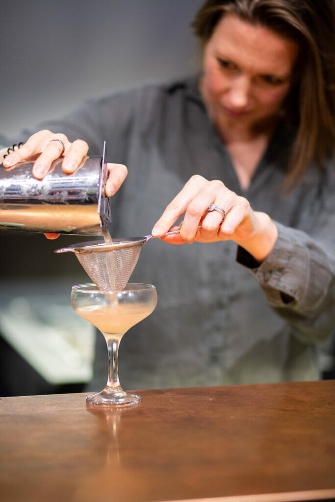 Woman pouring a drink into a glass during cocktail masterclass