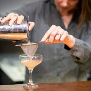 Woman pouring a drink into a glass during cocktail masterclass